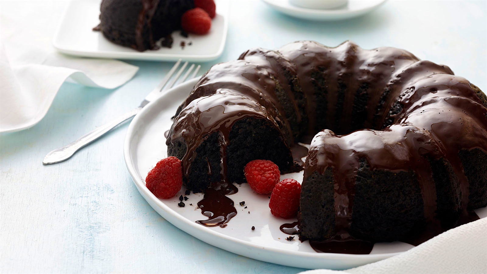 Lucious chocolate-glazed chocolate bundt cake garnished with raspberries